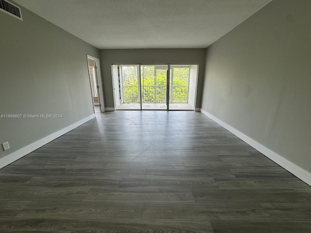 spare room featuring dark wood-type flooring and a textured ceiling