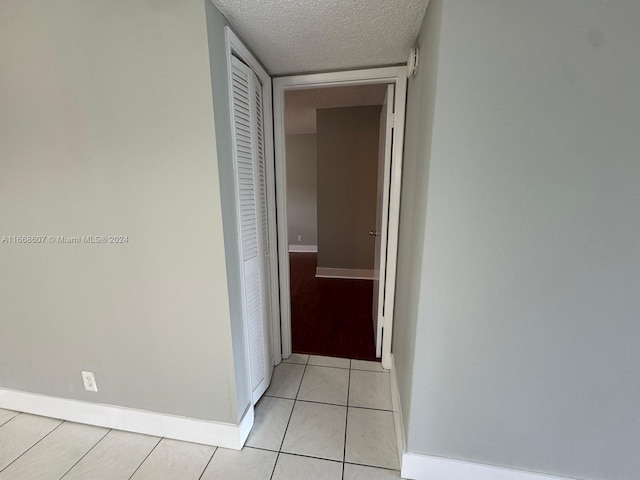 hall with a textured ceiling and light tile patterned floors