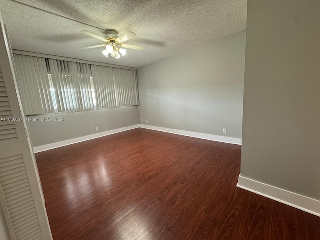 spare room with dark wood-type flooring, ceiling fan, and a textured ceiling