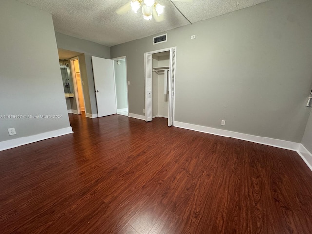 unfurnished bedroom with ceiling fan, dark wood-type flooring, a closet, and a textured ceiling