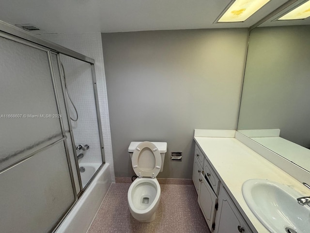 full bathroom with tile patterned floors, combined bath / shower with glass door, toilet, and vanity