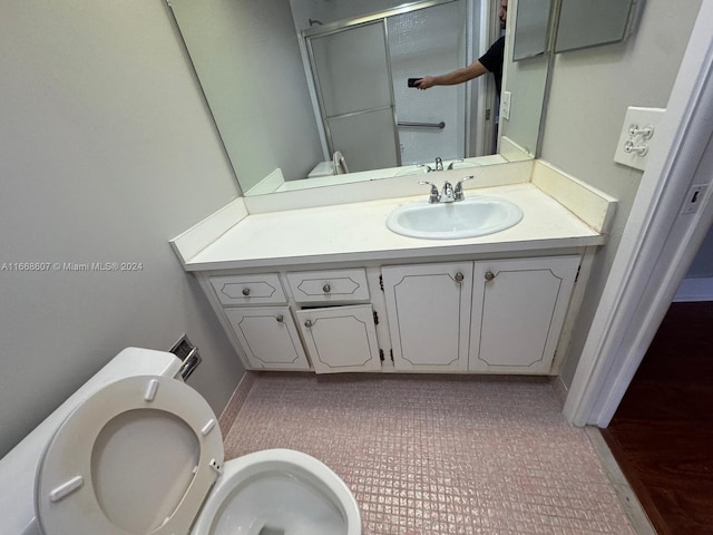 bathroom featuring vanity, toilet, and a shower with shower door