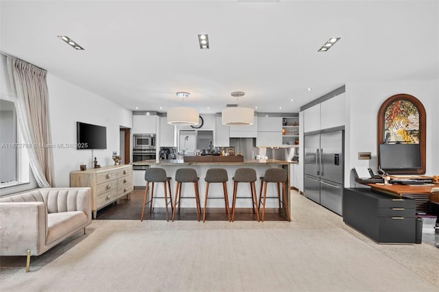 kitchen with a large island, pendant lighting, white cabinets, and built in appliances