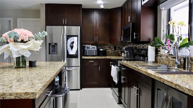 kitchen with light stone countertops, sink, backsplash, stainless steel appliances, and light tile patterned floors