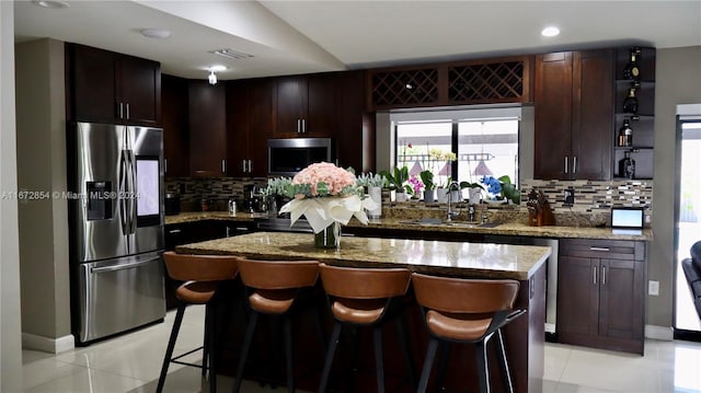 kitchen with stone counters, stainless steel appliances, decorative backsplash, and a kitchen island