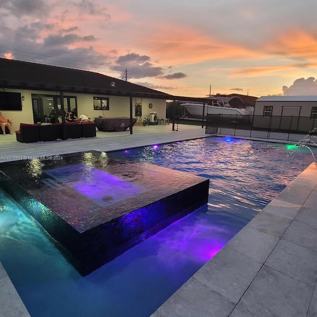 pool at dusk featuring an outdoor hangout area, pool water feature, and a patio