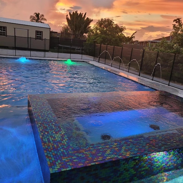 pool at dusk featuring pool water feature