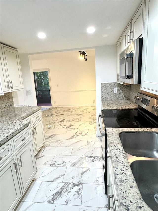 kitchen with decorative backsplash, appliances with stainless steel finishes, and light stone countertops