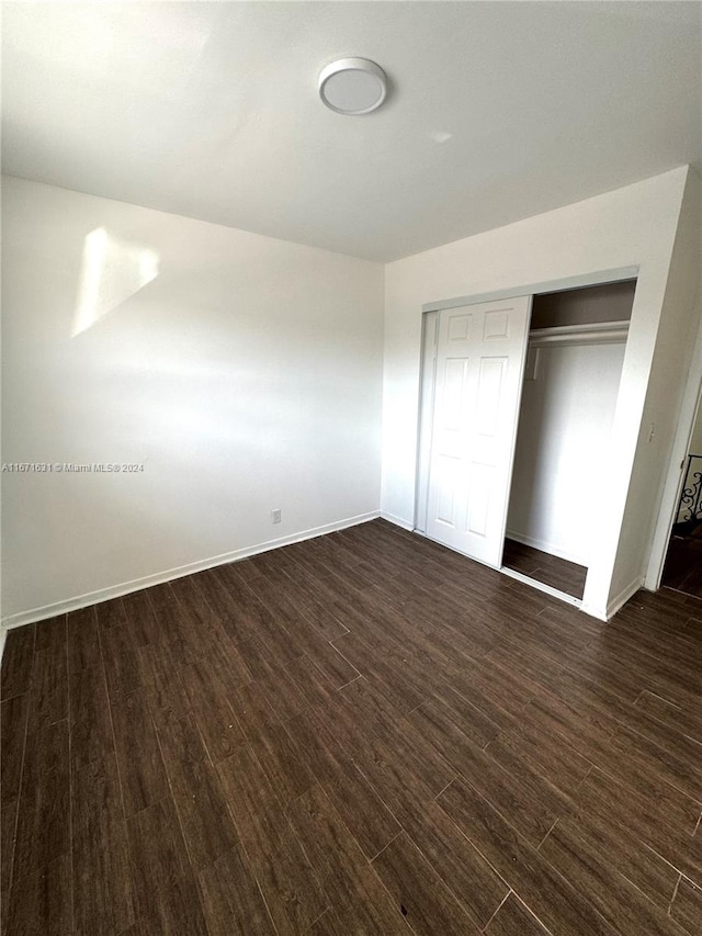 unfurnished bedroom featuring a closet and dark hardwood / wood-style flooring