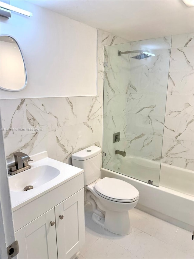 full bathroom with tiled shower / bath combo, toilet, vanity, and tile walls