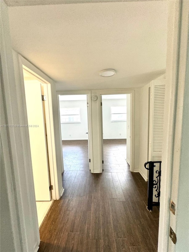 hallway with a textured ceiling and dark wood-type flooring