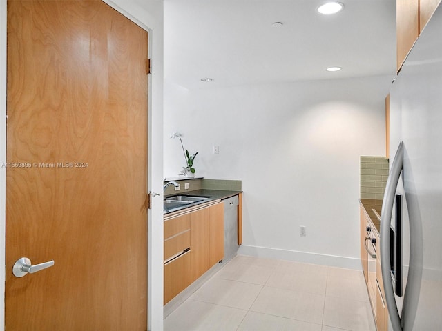 kitchen with appliances with stainless steel finishes, sink, and light tile patterned floors