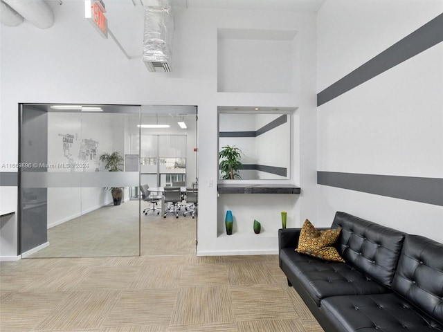 carpeted living room featuring a towering ceiling