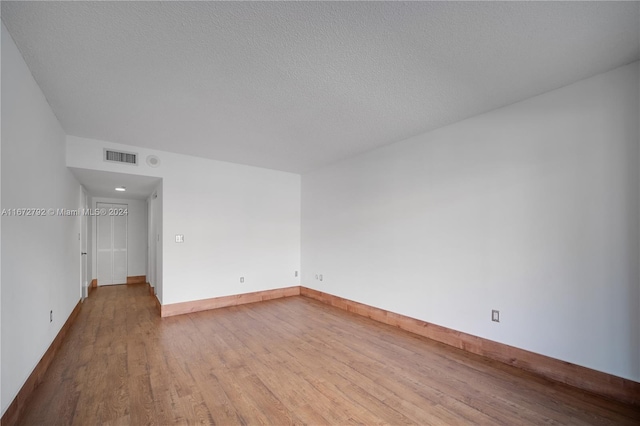 unfurnished room with light wood-type flooring and a textured ceiling