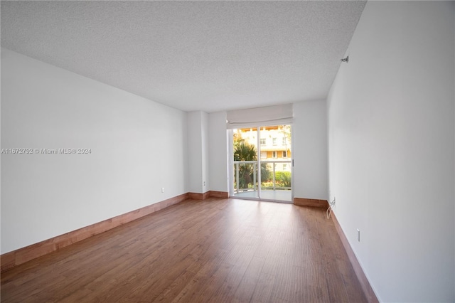 8855 Collins Ave Unit 2D, Surfside, FL 33154 - empty room with wood finished floors, a textured ceiling, and baseboards