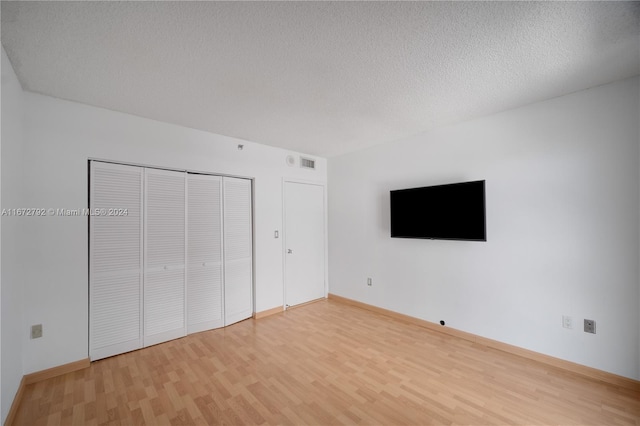 unfurnished bedroom with wood-type flooring, a textured ceiling, and a closet