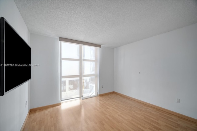 8855 Collins Ave Unit 2D, Surfside, FL 33154 - unfurnished room featuring light wood finished floors, a textured ceiling, and baseboards