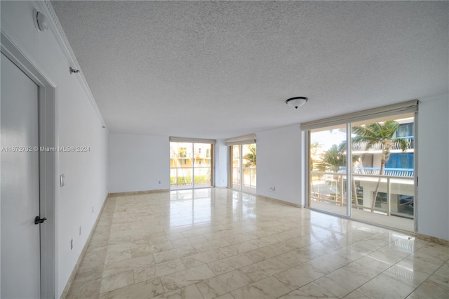8855 Collins Ave Unit 2D, Surfside, FL 33154 - empty room with plenty of natural light, marble finish flooring, baseboards, and a textured ceiling
