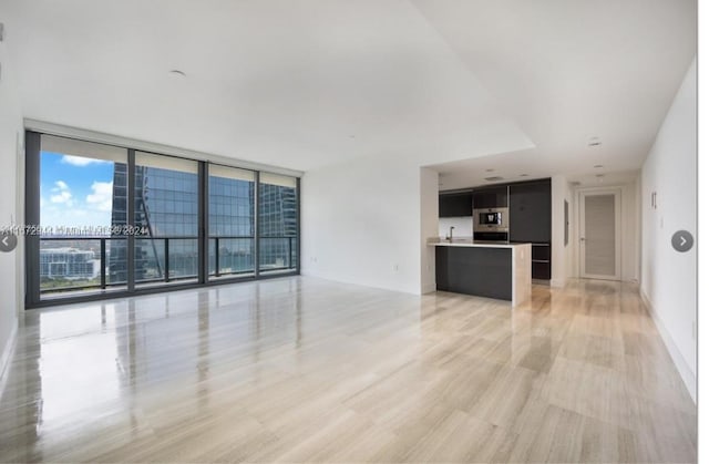 unfurnished living room featuring a wall of windows and light wood-type flooring