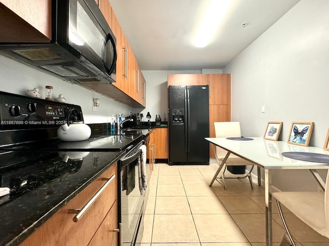 kitchen featuring dark stone countertops, sink, light tile patterned flooring, and black appliances