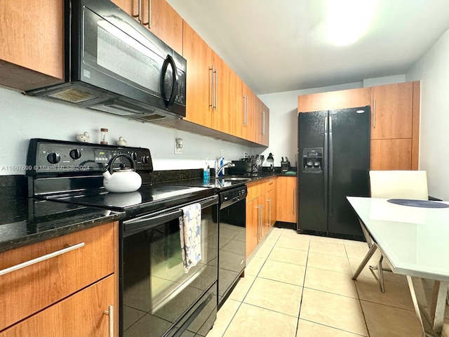 kitchen featuring dark stone counters, sink, light tile patterned floors, and black appliances