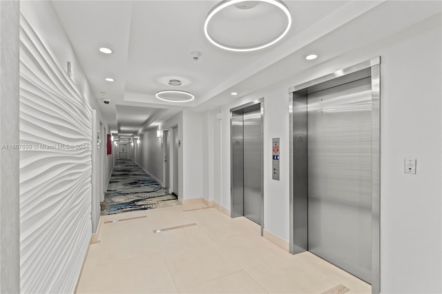 hall featuring light tile patterned floors and elevator