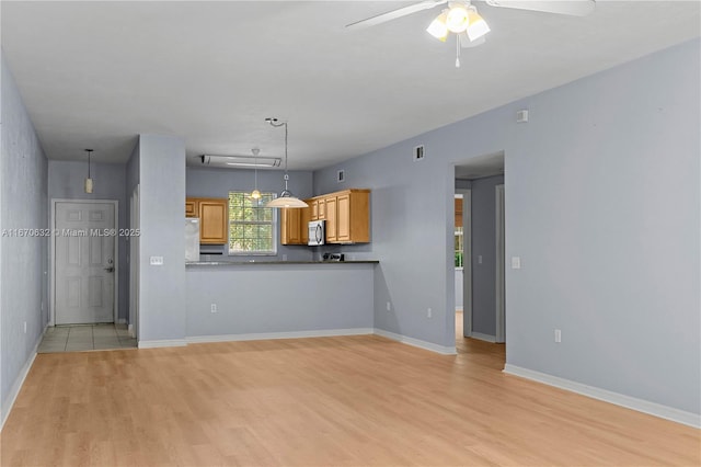 unfurnished living room featuring ceiling fan and light wood-type flooring