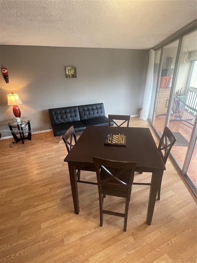 dining area with a textured ceiling and light hardwood / wood-style floors