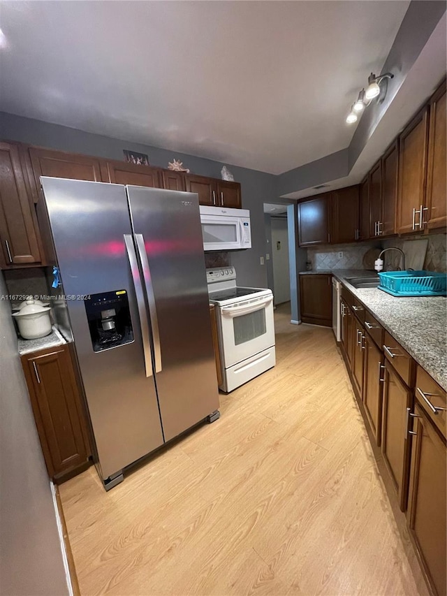 kitchen featuring decorative backsplash, light hardwood / wood-style floors, stainless steel appliances, and light stone counters