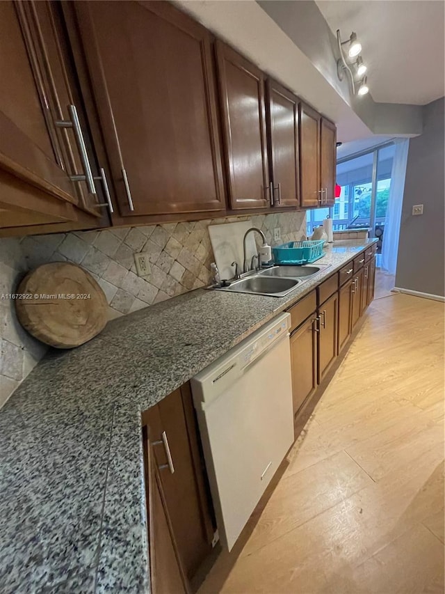 kitchen featuring dark stone counters, decorative backsplash, dishwasher, and sink