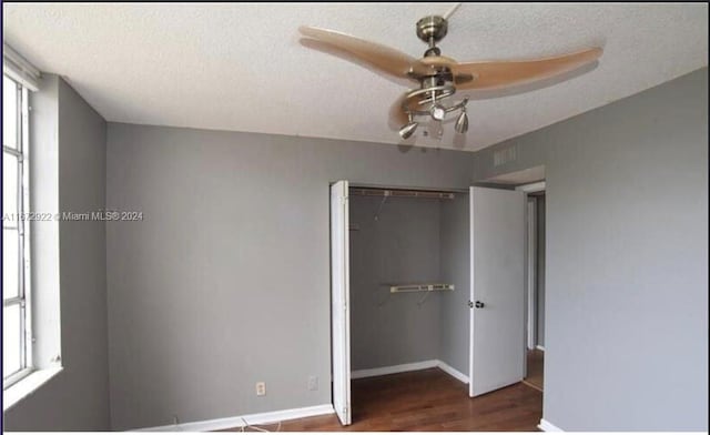 unfurnished bedroom featuring dark hardwood / wood-style flooring, a closet, ceiling fan, and a textured ceiling