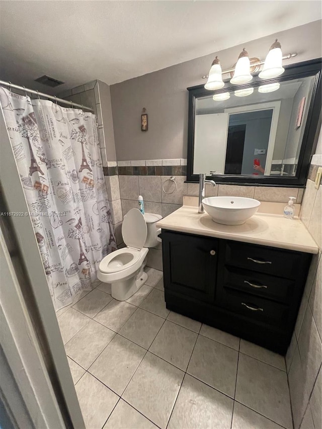 bathroom featuring vanity, tile patterned floors, walk in shower, tile walls, and toilet