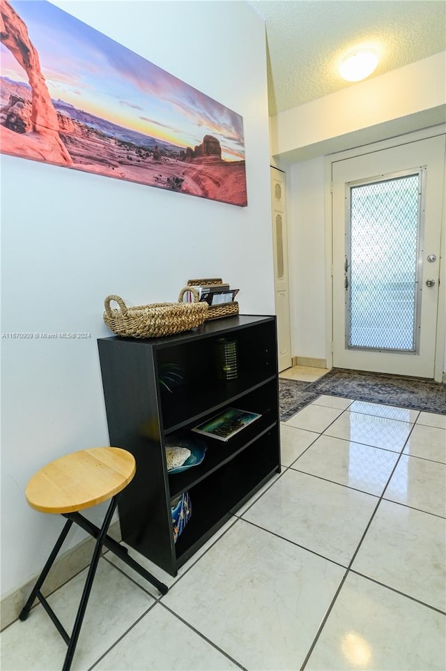 doorway with a textured ceiling and tile patterned flooring