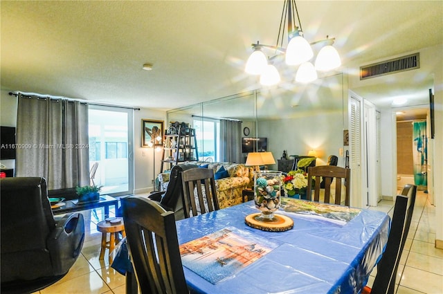 dining space with an inviting chandelier, a textured ceiling, and light tile patterned floors