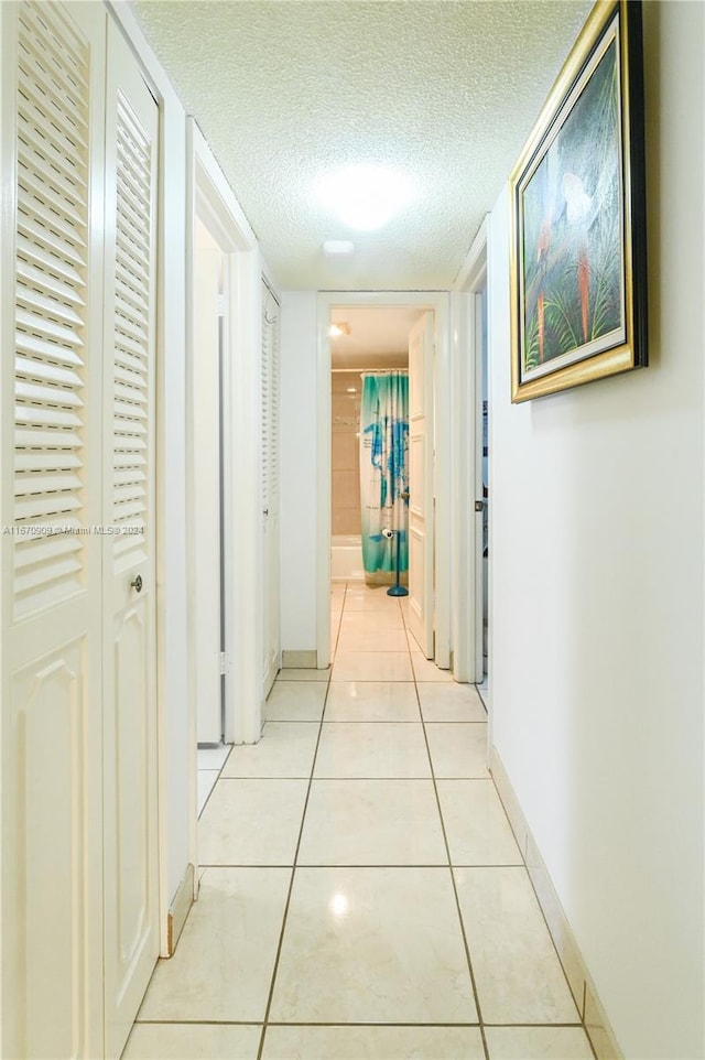 hall featuring a textured ceiling and light tile patterned floors