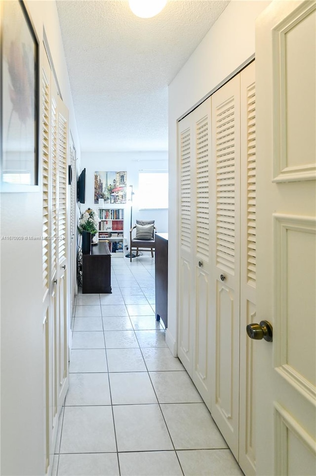 hall with light tile patterned flooring and a textured ceiling