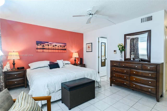 bedroom featuring ceiling fan, light tile patterned floors, and a textured ceiling