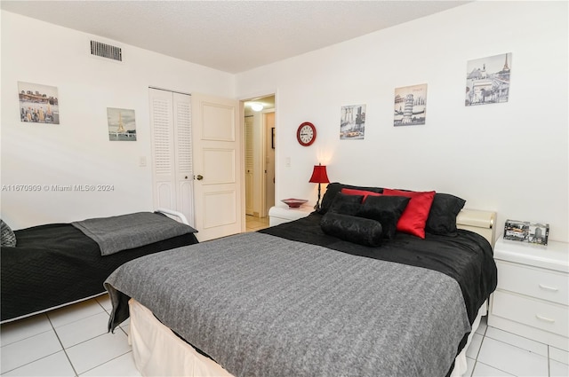 bedroom with light tile patterned flooring, a closet, and a textured ceiling