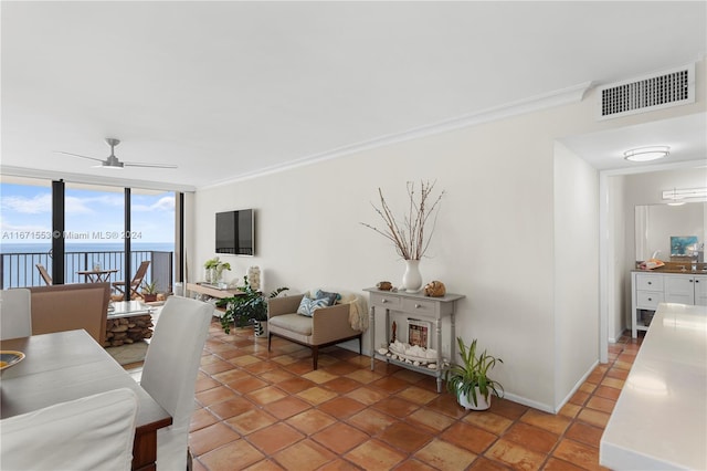 living room featuring crown molding, a water view, ceiling fan, and expansive windows