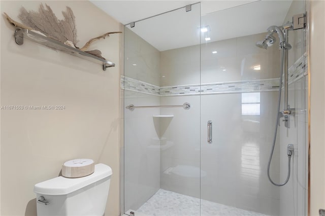 bathroom with toilet and a shower with shower door