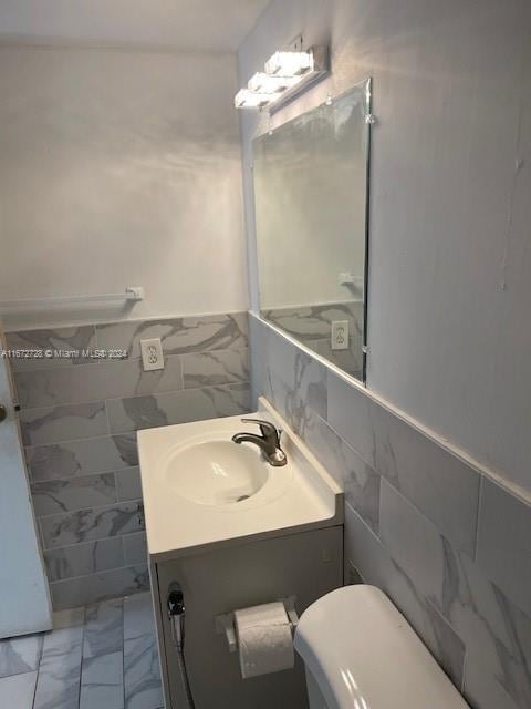 bathroom with vanity, tile walls, and toilet