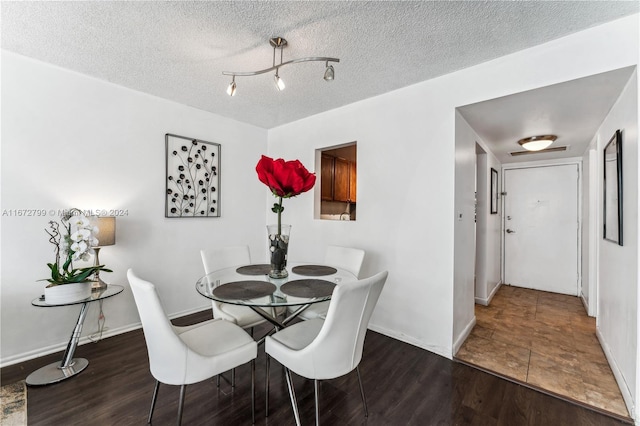 dining area featuring a textured ceiling and dark hardwood / wood-style floors