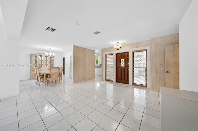 entrance foyer with a notable chandelier, wood walls, and light tile patterned floors