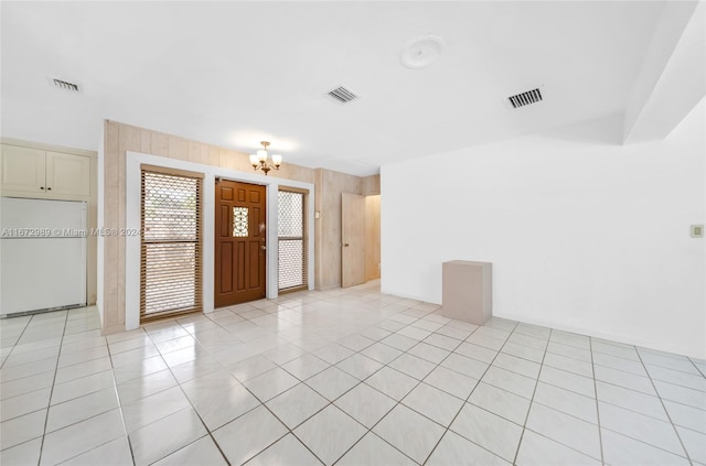 tiled empty room with a notable chandelier and wood walls