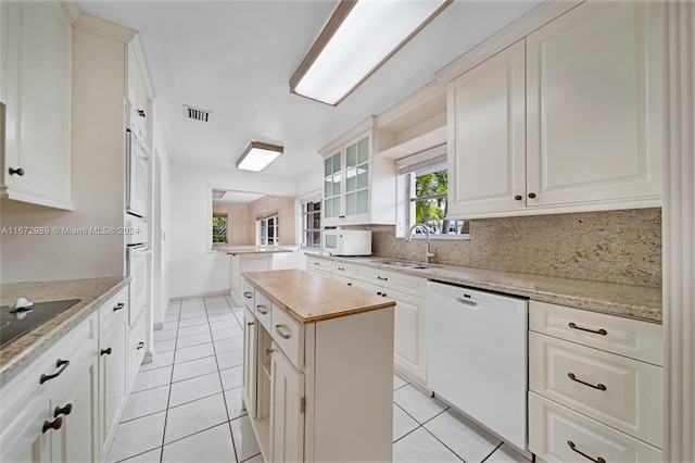 kitchen with white appliances, butcher block counters, white cabinetry, and a kitchen island