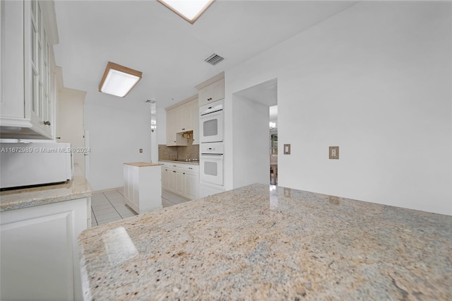 kitchen featuring light stone counters, oven, and light tile patterned floors