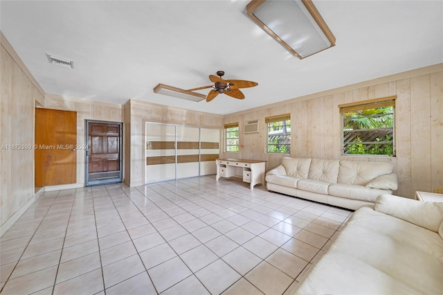 living room featuring wood walls, ceiling fan, and light tile patterned floors