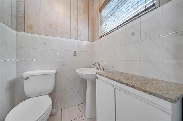 bathroom featuring tile walls, wooden walls, toilet, and tile patterned floors