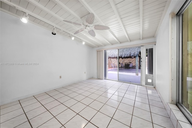 tiled spare room featuring vaulted ceiling with beams, rail lighting, and ceiling fan