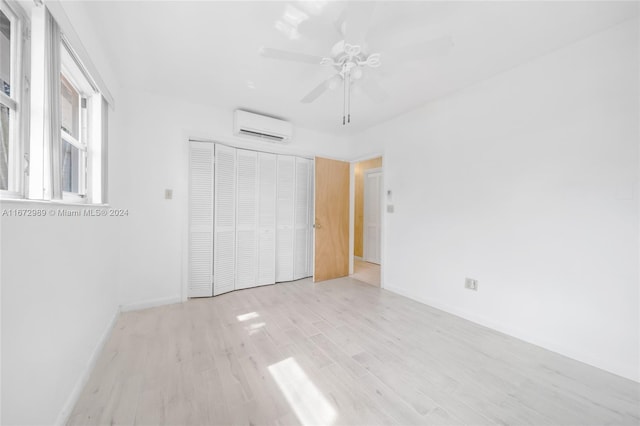 unfurnished bedroom with a closet, light hardwood / wood-style floors, ceiling fan, and a wall mounted air conditioner